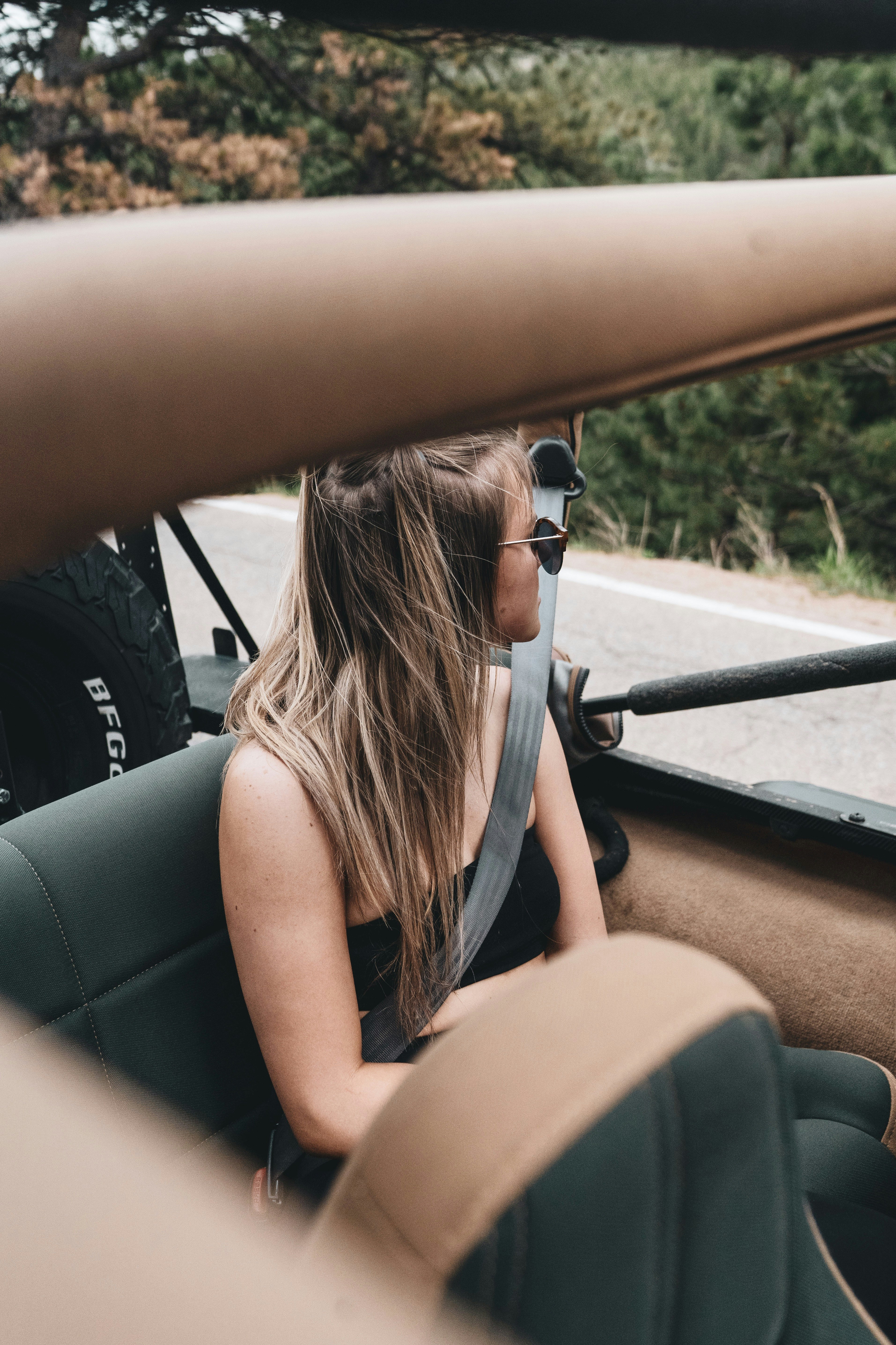 woman in black tank top driving car during daytime